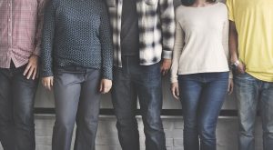 Five friends standing against a wall.