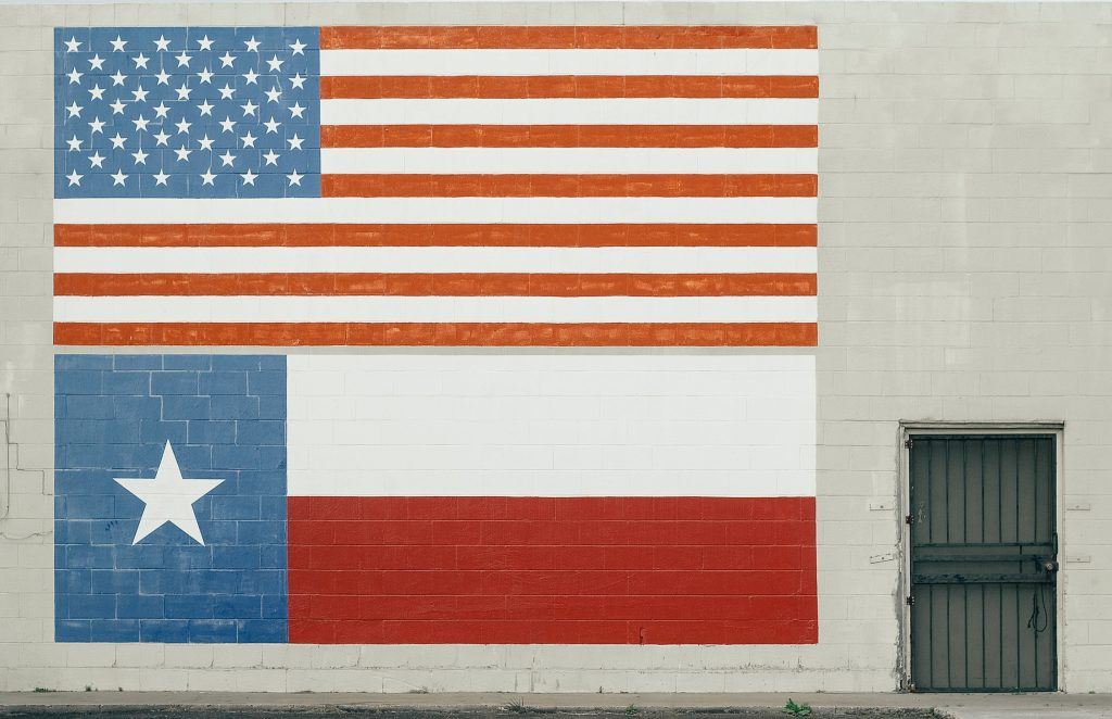 US and Texas flags on a wall.