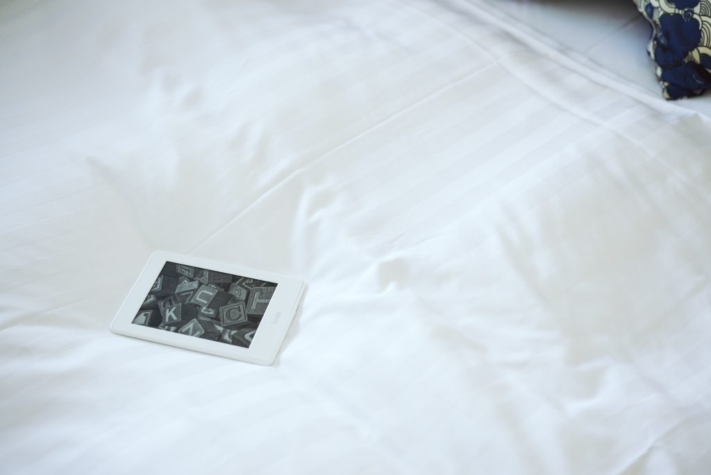 Kindle on standby on a bed.