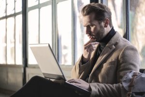 Man looking confusedly at his laptop.