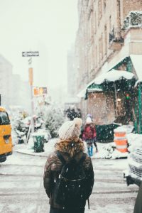 Woman wearing a white hat in NYC streets during a blizzard