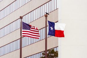Texas and US flags on poles next to each other.