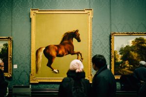 a painting of a horse in a museum and two people observing it