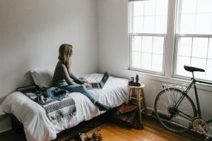 woman on a bed with lap top planning to maximize space in your NYC apartment